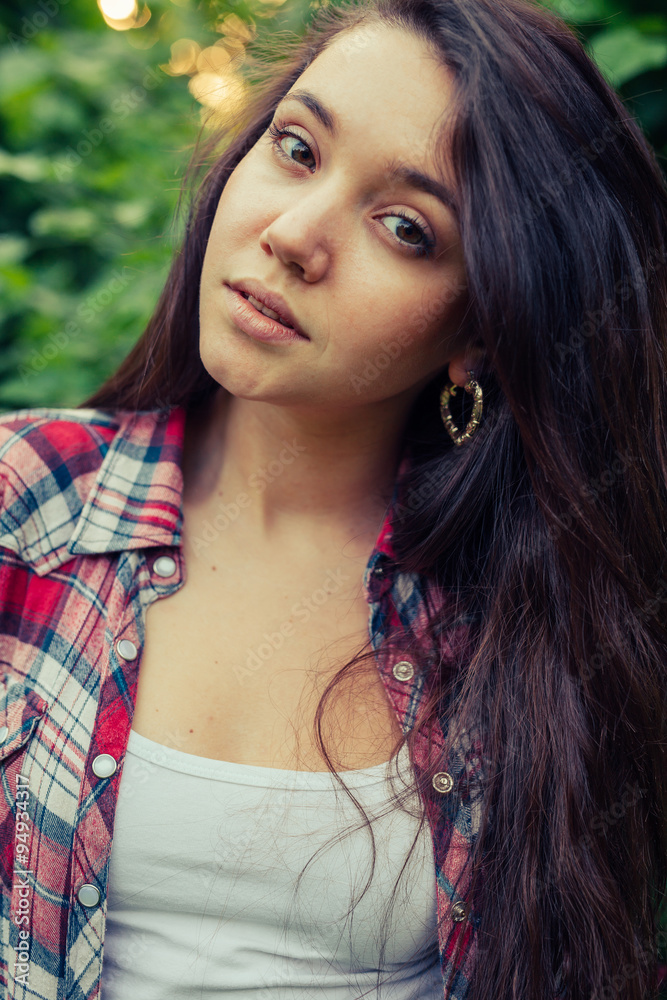Brown hair girl sitting on the grass in the park and posing to the picture. Brown hair girl sitting on the grass in the park and posing to the picture.