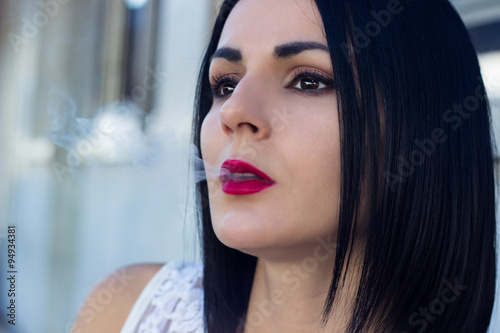 Young woman sitting and smokes a cigar