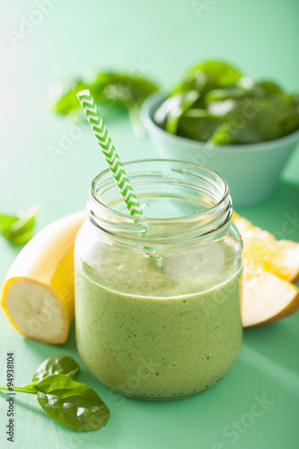 healthy green spinach smoothie with mango banana in glass jar