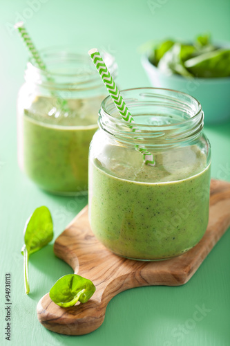 healthy green spinach smoothie with mango banana in glass jar