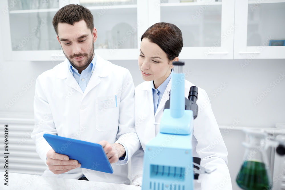 scientists with tablet pc and microscope in lab scientists with tablet pc and microscope in lab