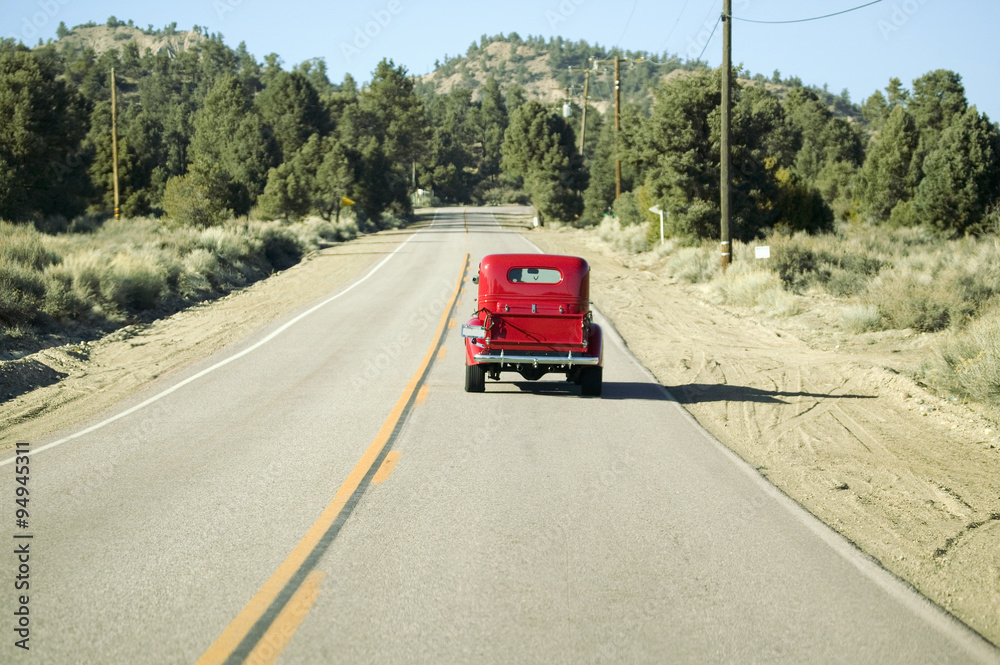 A restored bright Red Roadster hotrod pickup truck, mid-30's, drives rural highway in Kern County near Lockwood Valley, CA A restored bright Red Roadster hotrod pickup truck, mid-30's, drives rural highway in Kern County near Lockwood Valley, CA