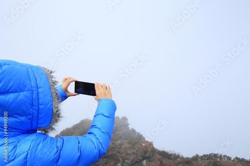 hiker hands taking photo with smartphone on mountain peak