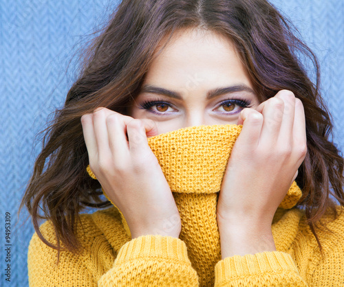 Beautiful natural young shy brunette woman with smiling eyes wearing knitted sweater 