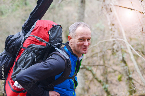 Hiker with a backpack and a guitar goes in the autumn woods.