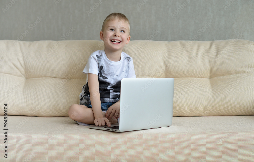 Little boy sitting with laptop on the couch at home Little boy sitting with laptop on the couch at home