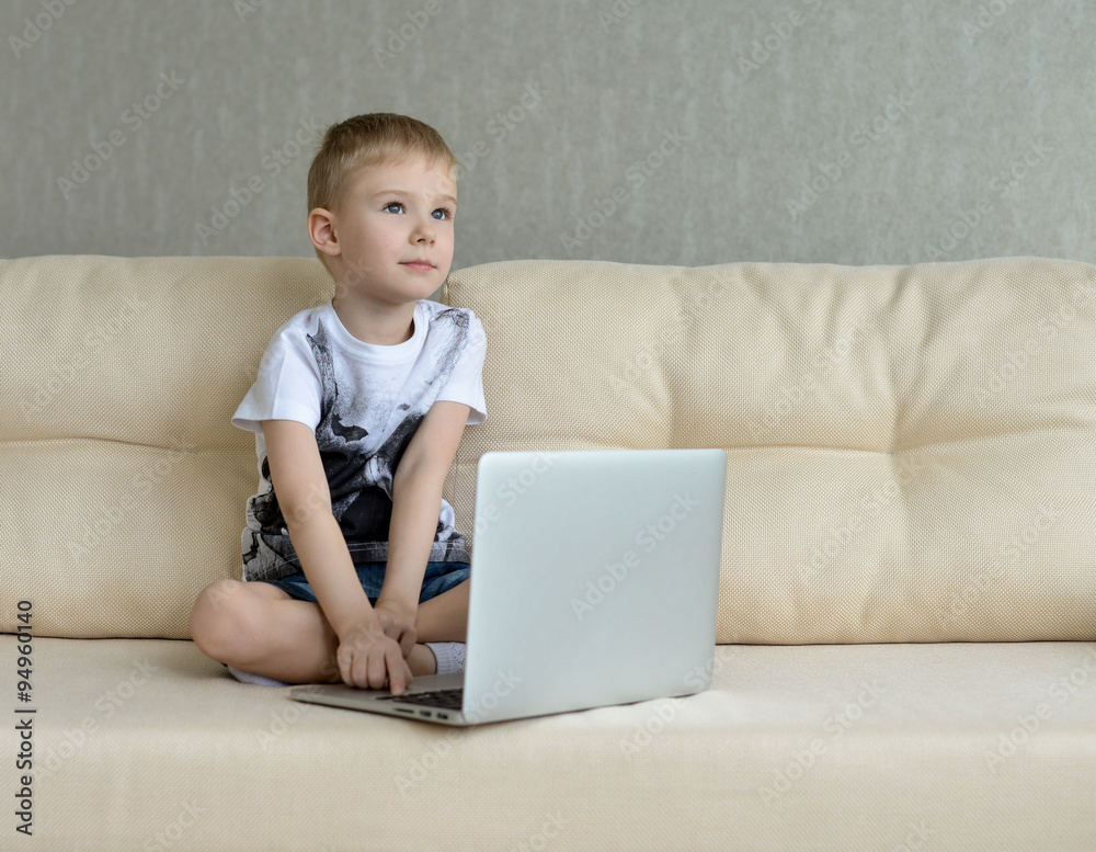 Little  boy sitting with laptop on the couch at home