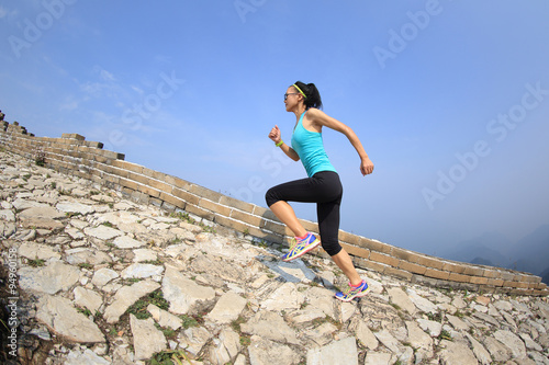 woman runner athlete running on trail at chinese great wall . woman fitness jogging workout wellness concept.