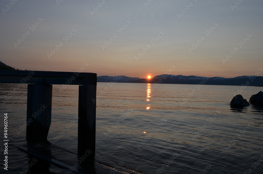 Wooden jetty in lake Torneträsk, Abisko, with midnight sun