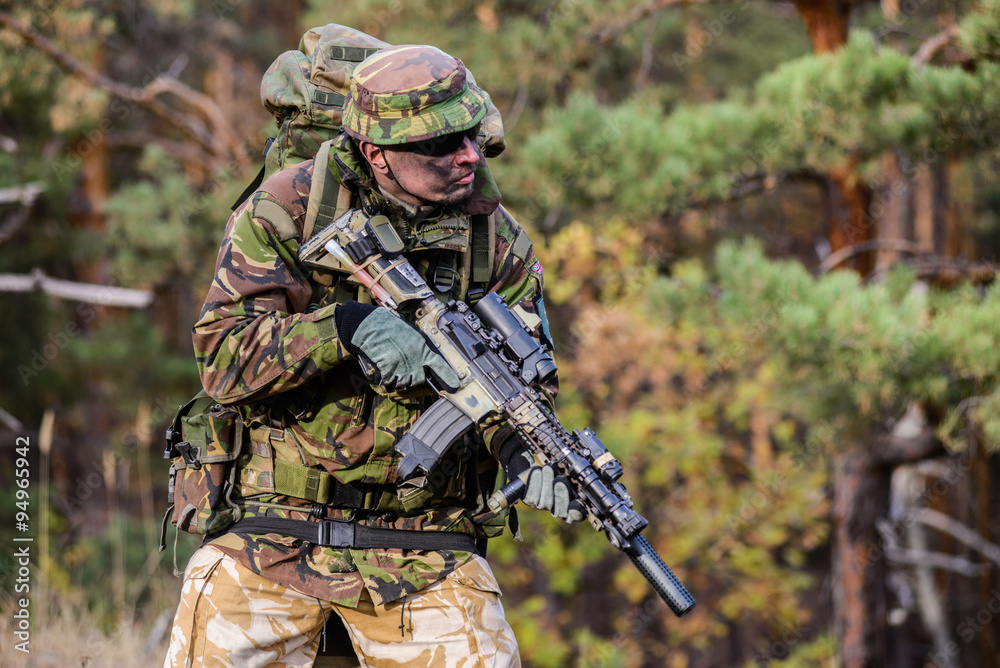 Gunner in forest/Soldier with military backpack and rifle against the background of the forest