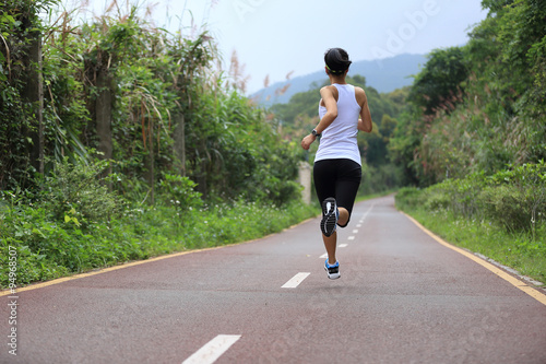 Runner athlete running on forest trail. woman fitness jogging workout wellness concept. © lzf