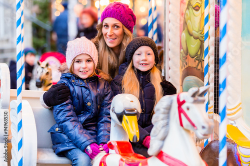 Familie fährt Karussell auf dem Weihnachtsmarkt