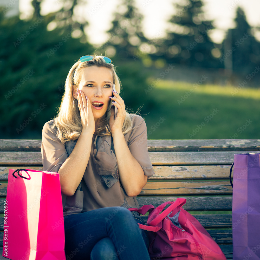 Young surprised woman sitting on a bench after shopping Young surprised woman sitting on a bench after shopping