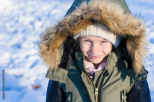 Little adorable girl with beautiful green eyes in snow sunny winter day