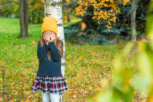 Φωτογραφία Little girl playing hide and seek near tree in autumn park