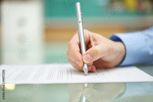 mans hand is  writing document at home on desk photo
