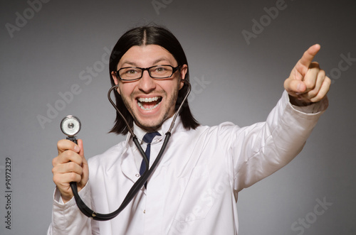 Young physician with stethoscope against gray