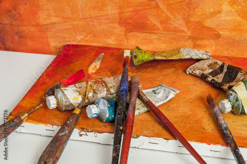 Painting brush and a palette knife on orange canvas desk