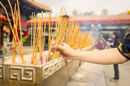 Photos prayer places incense sticks on ash vase at a buddhist-taoist-confucian temple i