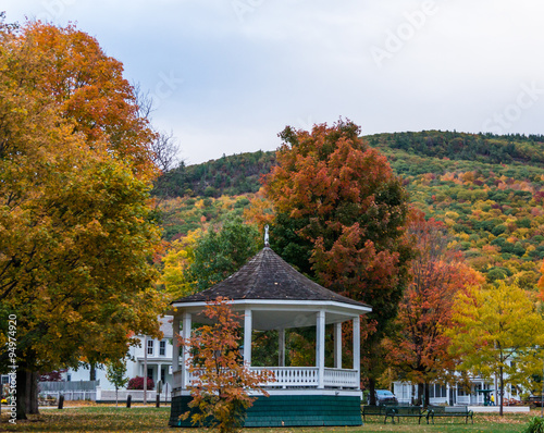 Slika na platnu white gazebo or bandstand in village park with trees in full fall autumn  colors