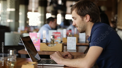 Young businessman using at laptop in cafe