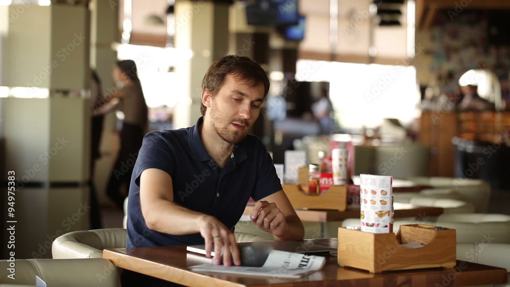 man reading the newspaper and working at a laptop man reading the newspaper and working at a laptop