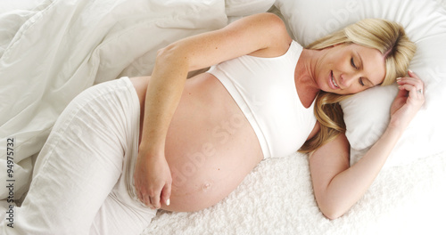 Pregnant woman lying on bed smiling