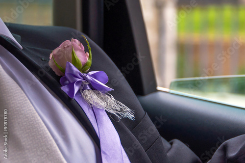 Groom's Boutonniere with a pink rose inside a car by a window, going to the wedding photo