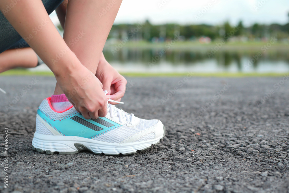 Women tying sport shoe prepare jogging at park.