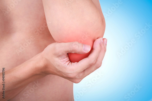 Close up suffering male pain in elbow on blue background.