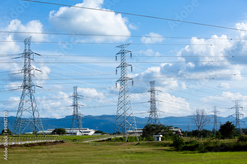 High voltage lines and power pylons in a flat and green agricult