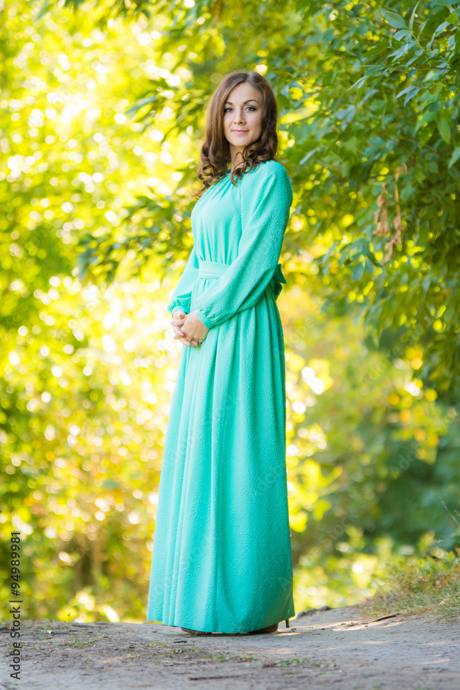 A girl in a long dress against a background of blurred forest
