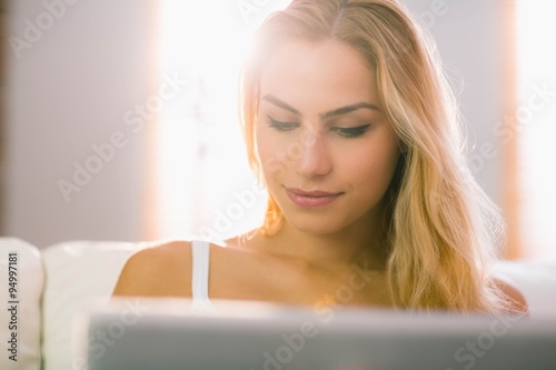 Pretty blonde using laptop on couch