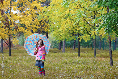 beautiful little girl with umbrella in park autumn season