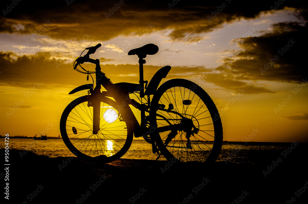 Fototapeta premium Silhouette of mountain bike with sunset sky at sea