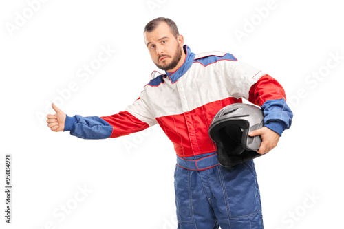 Young car racer holding a helmet and hitchhiking