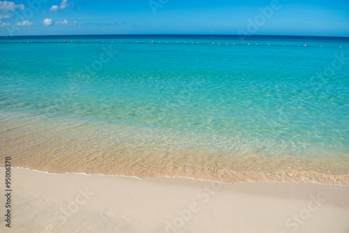 Azure turquoise calm sea, clear blue sky, sandy beach and flat horizon