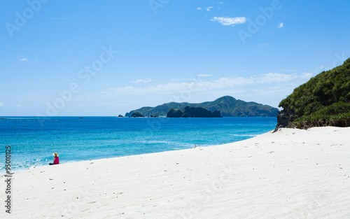 Woman sitting on deserted tropical island beach, Okinawa, Japan