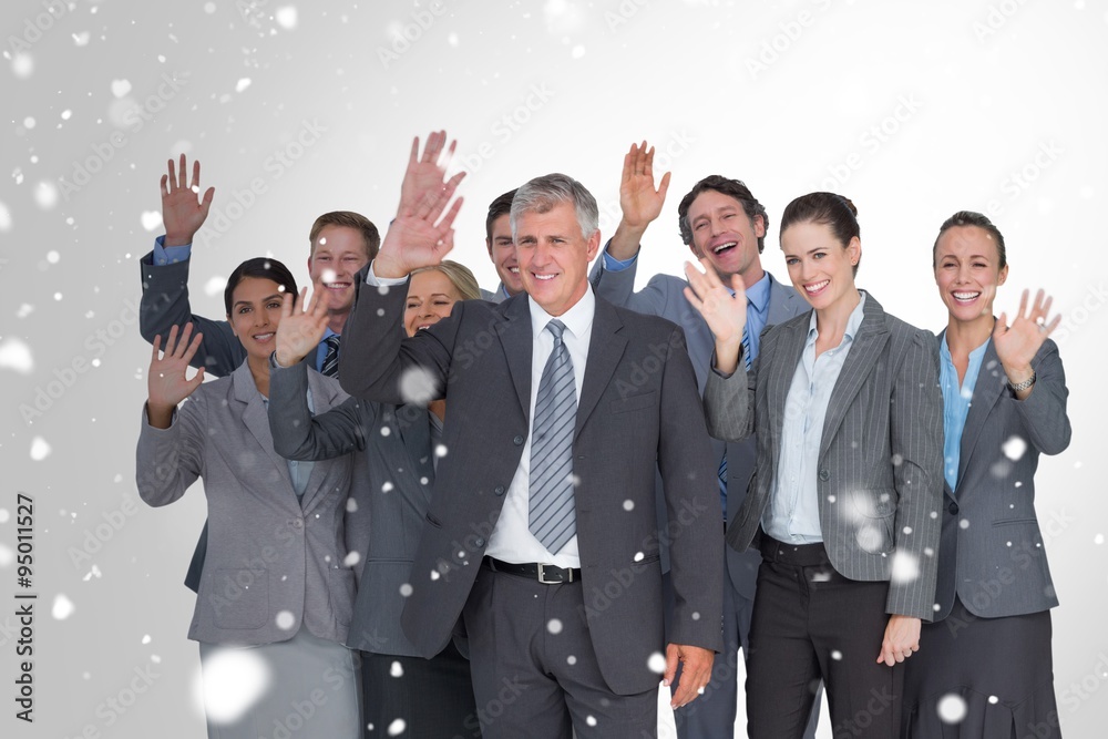 Composite image of smiling business team waving at camera