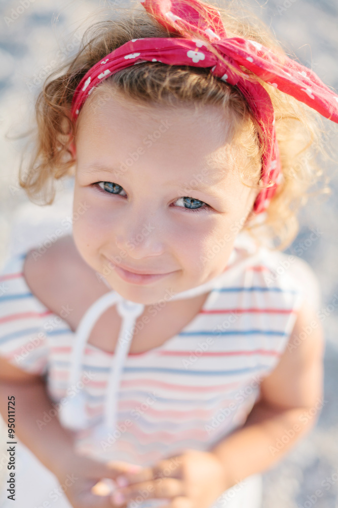 Adorable happy smiling little girl with curly hair on beach vaca Adorable happy smiling little girl with curly hair on beach vaca