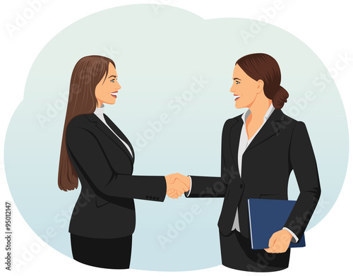 Two businesswomen giving handshake in an office. Teamwork and cooperation.