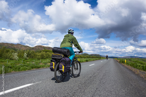 Biker rides on road at sunny summer day in Iceland