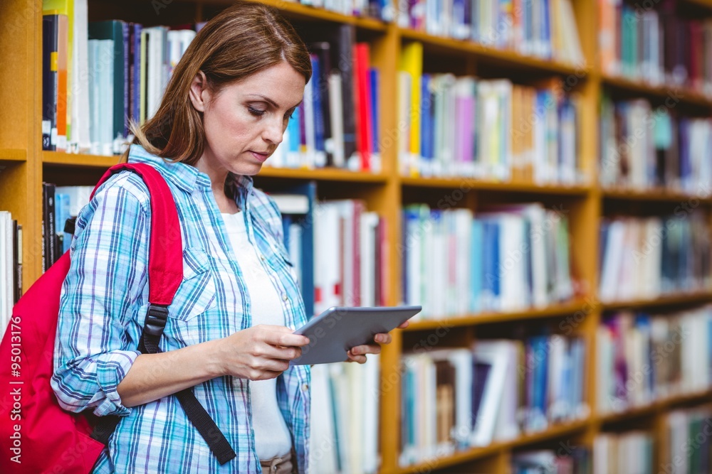 Mature student in the library using tablet Mature student in the library using tablet