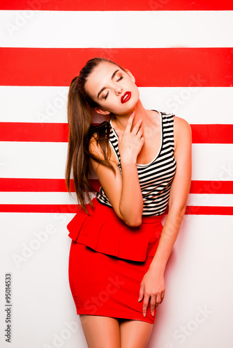Glamorous girl with red lips posing against the striped backgrou