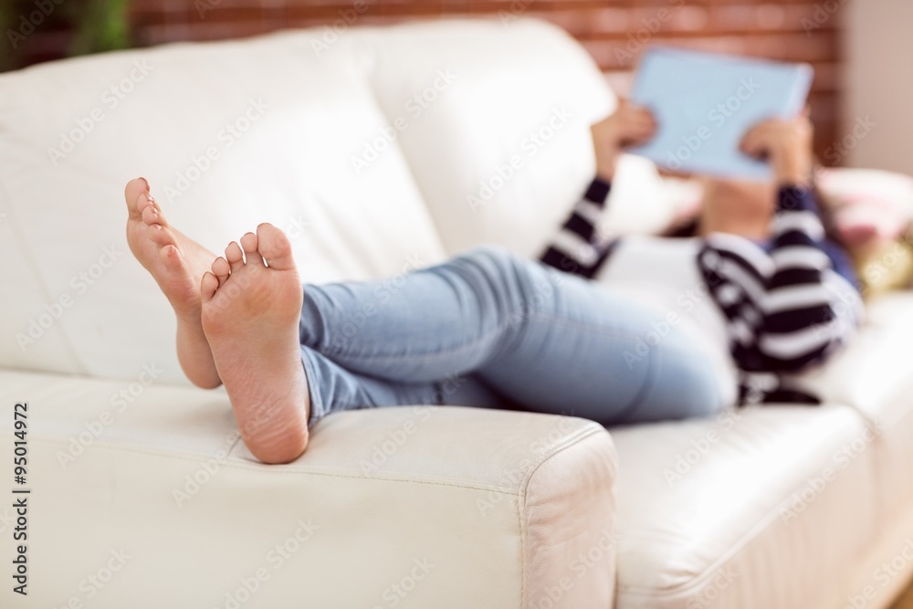 © WavebreakmediaMicro - Asian woman lying on the couch using tablet