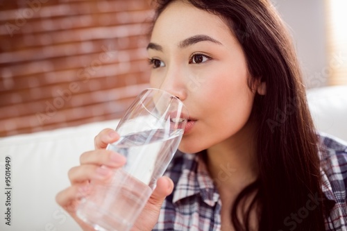Asian woman on the couch drinking water 
