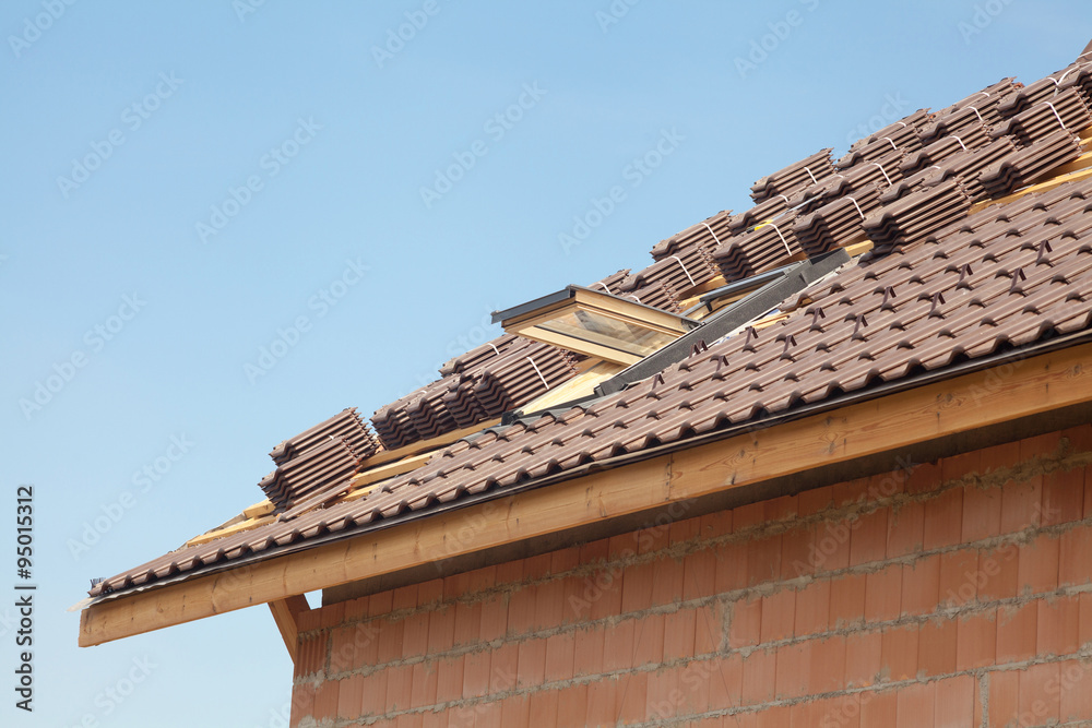 New roof with open skylight, natural red tile against blue sky