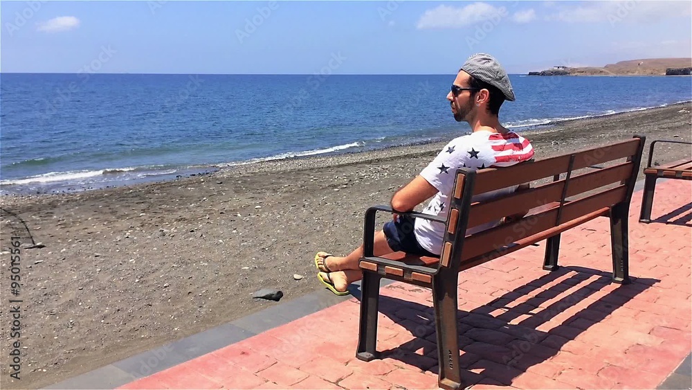 Guy sitting on bench at seafront