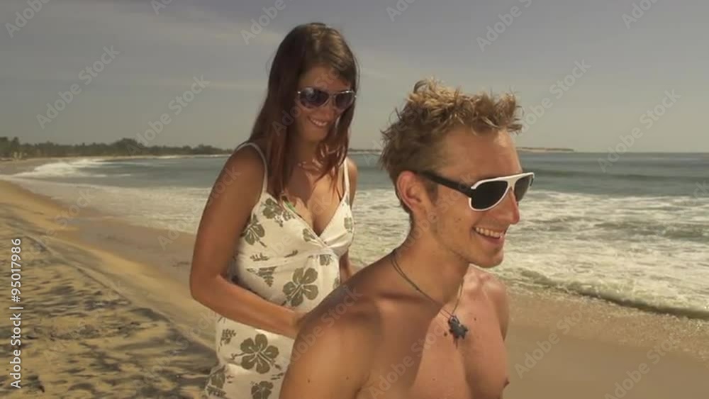 Girlfriend greasing her boyfriend with suntan lotion Girlfriend greasing her boyfriend with suntan lotion
