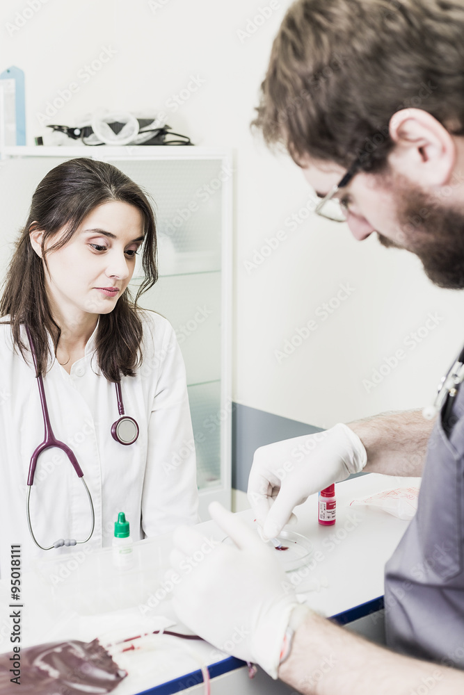 Fototapeta premium Doctor woman sitting at a table in a white coat male Doctor making blood